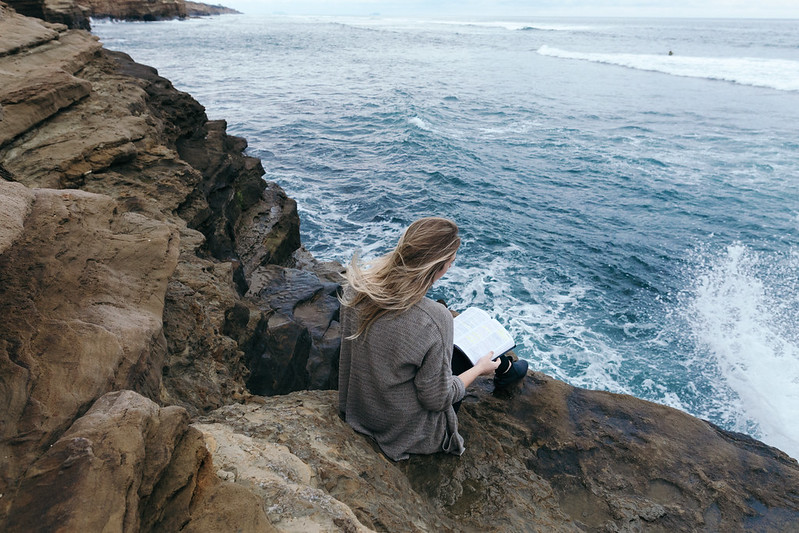 Environmental studies promo photo- student sitting by ocean