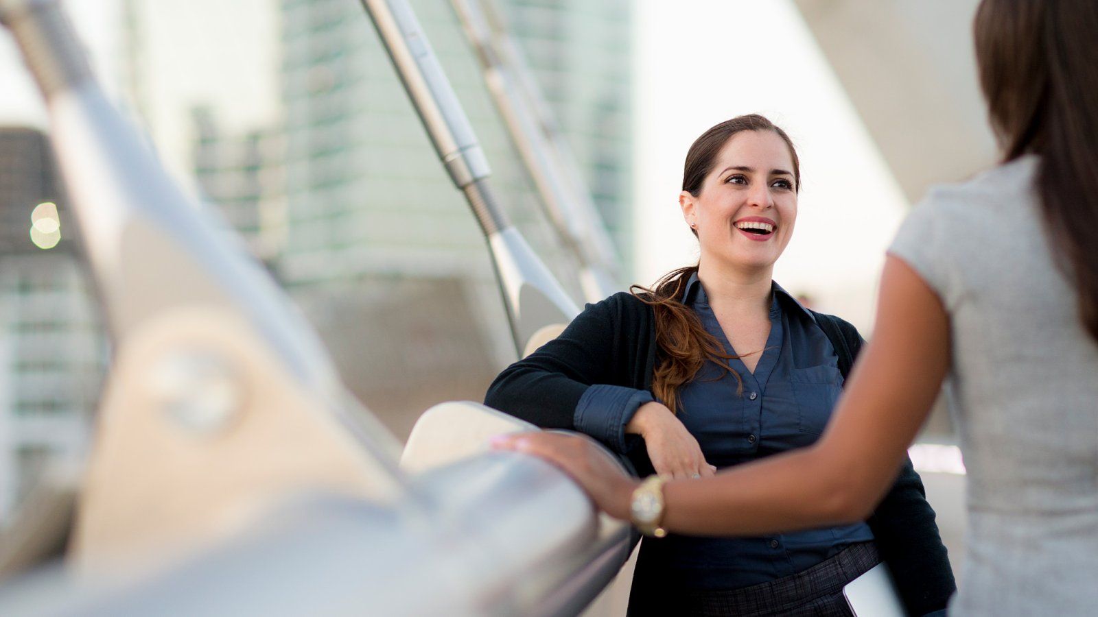 Woman converses with another woman on a pedestrian bridge